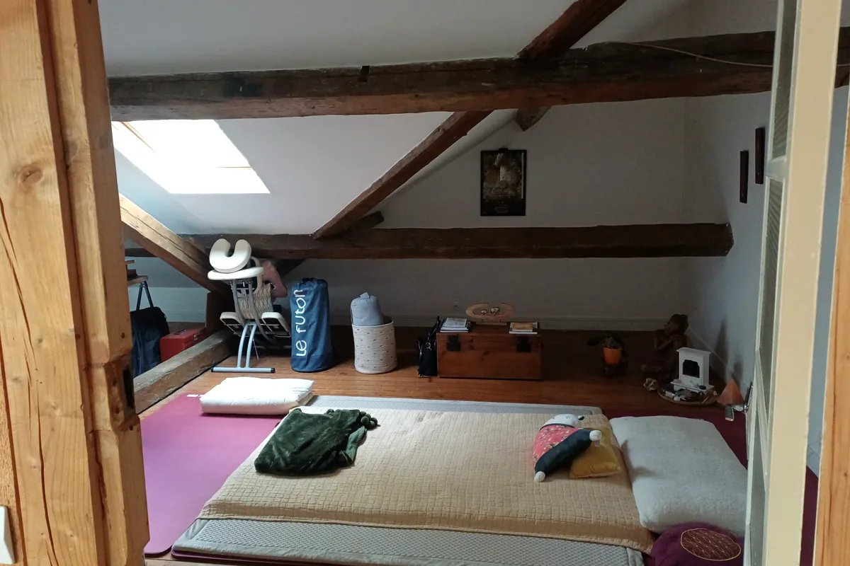 Le dojo, espace de pratique du shiatsu : futon et poutres apparentes sous la lumière naturelle